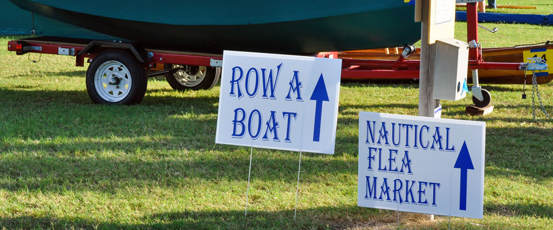 Signs pointing out direction to nautical flea market and row a boat