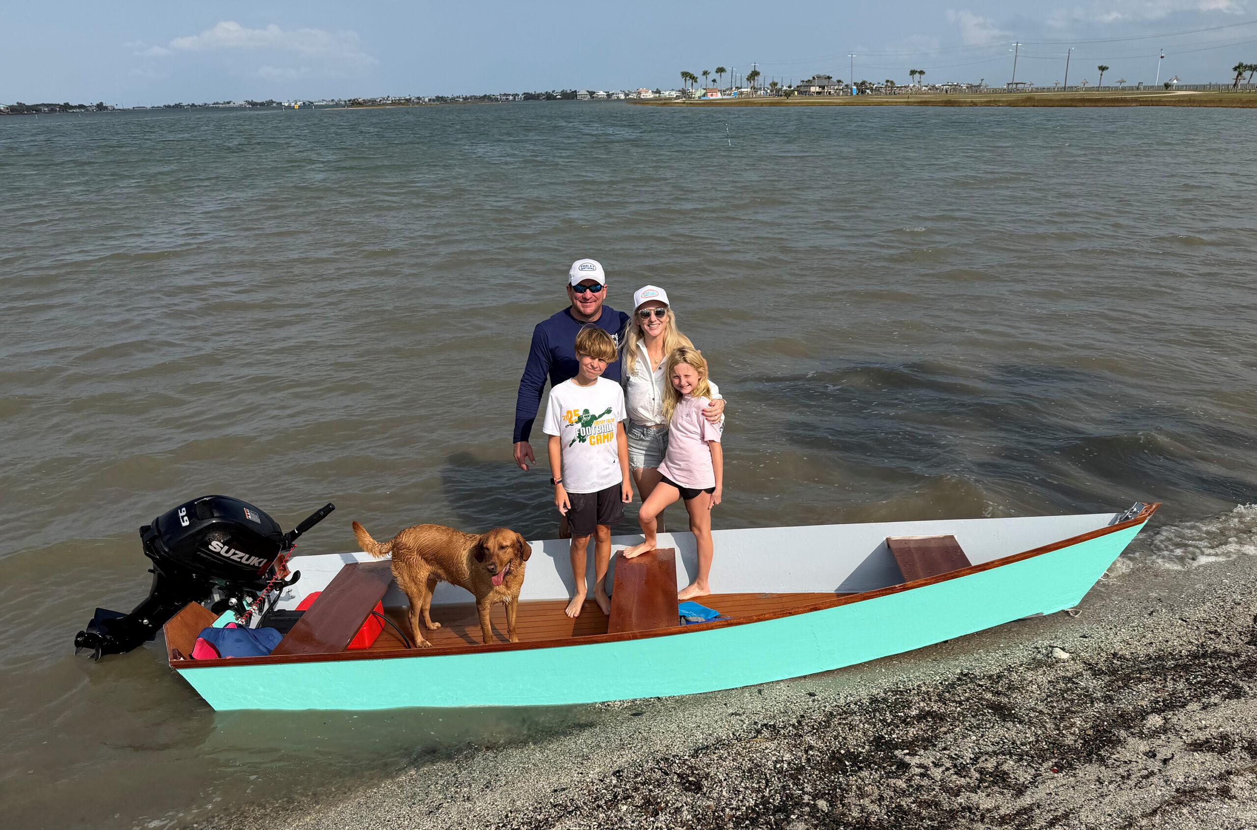 turquoise boat with family of four and a dog 